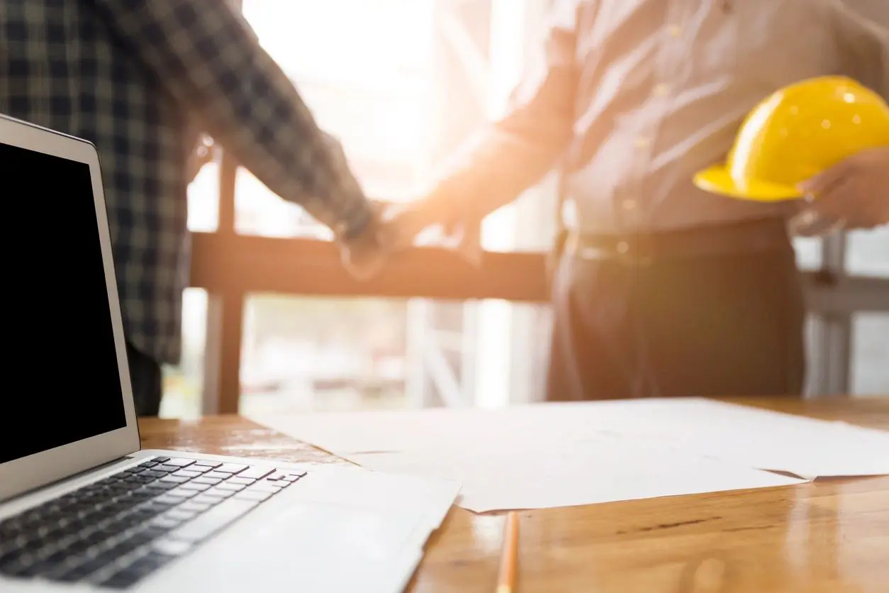 Two people holding hands over a table with papers.