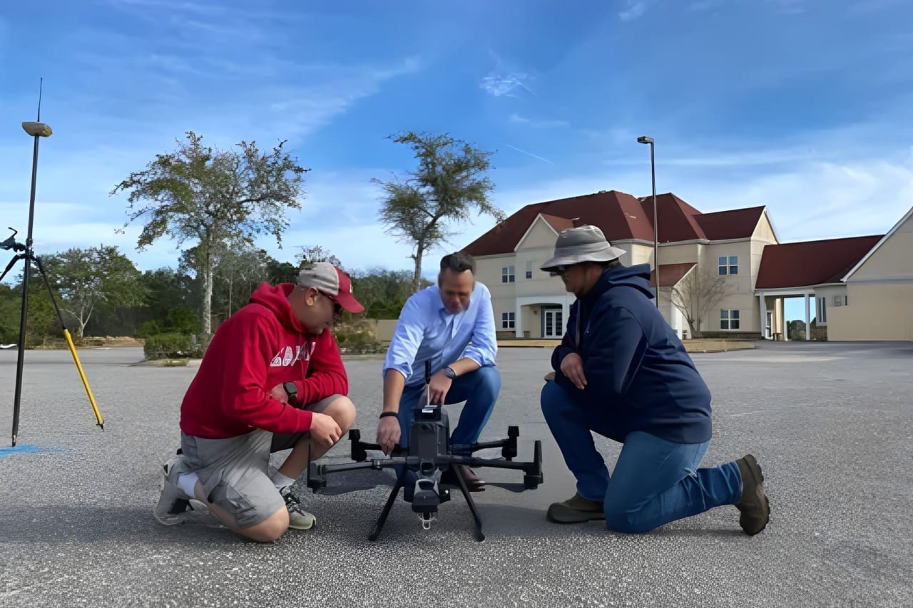 Three men are kneeling down to inspect a camera.